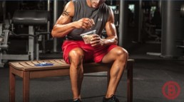 Fitter Typ sitzt im Gym und mischt seinen Proteinshake