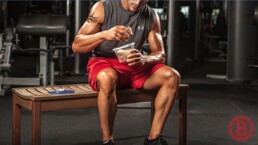 Fitter Typ sitzt im Gym und mischt seinen Proteinshake